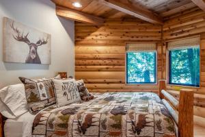 Dormitorio en cabaña de madera con cama y ventanas en Waterfall Lodge Yellowstone Vibes Ac Space, en Shaver Lake