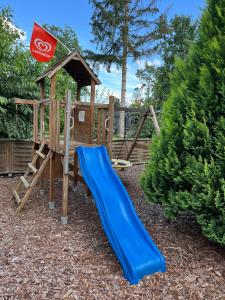 a playground with a blue slide and a house at CASALINO DI ANNA 2 in Wensickendorf