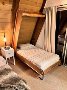 Schlafzimmer mit einem Bett und einem Beistelltisch in der Unterkunft Dogwood Peak Mid-century A-frame With Ac Style in Shaver Lake