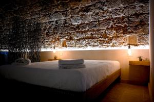ノートにあるLA GROTTA, luxury suite & Spaのレンガの壁のベッドルーム1室(白いベッド1台付)