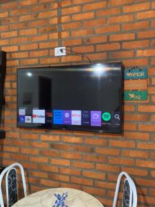a flat screen tv hanging on a brick wall at Chalé Topázio no Recanto Diamantina entre Palmeiras e Capão in Palmeiras