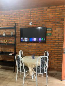 a table with two chairs and a tv on a brick wall at Chalé Topázio no Recanto Diamantina próximo ao Vale do Capão in Palmeiras