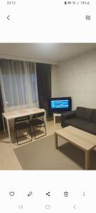 un salon avec un canapé, une table et une télévision dans l'établissement Apartment near tikkurila railwaystation with free parking, à Vantaa