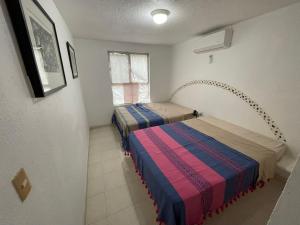 two beds in a small room with a window at Departamento céntrico Huatulco in Santa Cruz Huatulco