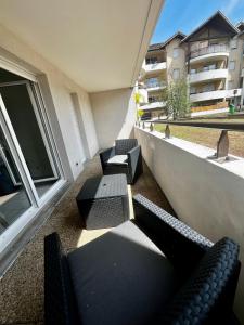 a balcony with chairs and tables on a building at Le Cosy l Proche Genève l Key Home Leman in Vétraz-Monthoux