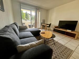 a living room with a couch and a television at Le Cosy l Proche Genève l Key Home Leman in Vétraz-Monthoux