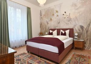 Villa Gloriette - BoutiqueAppartements am Wörthersee في بويرشاك آم فورثيرسي: غرفة نوم بسرير كبير وورق جدران