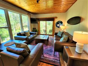 a living room with leather furniture and a wooden ceiling at Creekside Hot Tub-Walk to Beach-Uniquely Northern in Traverse City +41 photos