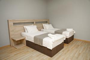 due letti singoli in una stanza con pavimenti in legno di Hotel Martini Kvariati a Kvariati