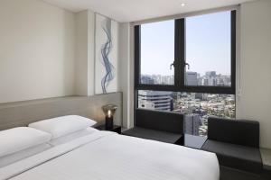 a bedroom with a bed and two chairs and a window at Fairfield by Marriott Seoul in Seoul