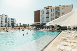 a swimming pool with chairs and people in the water at Dazur Coast Resort in Orikum