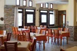 a dining room with tables and chairs and windows at Hotel Defkalion in Álli Meriá