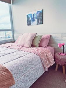 a bedroom with a bed with pink sheets and a pink lamp at Departamento céntrico, acogedor y bien equipado in Concepción