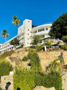 a large white building with palm trees and plants at Suite CasaBlanca Grand, la mejor vista de Acapulco in Acapulco