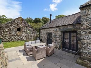 a patio with a table and chairs in front of a stone building at Beudy Bach in Llanbedr