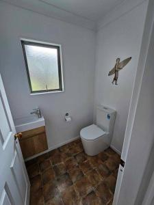 a small bathroom with a toilet and a window at Whangamata Harbour Haven in Whangamata +19 photos