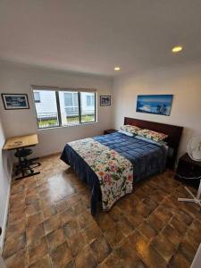 a bedroom with a bed and a desk and two windows at Whangamata Harbour Haven in Whangamata