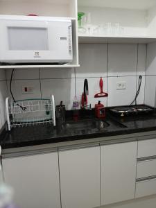 a kitchen with a sink and a microwave at Praia Guilhermina Sol Mar in Praia Grande +12 photos
