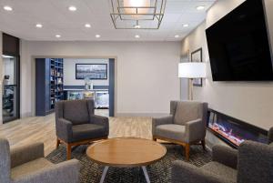 a waiting room with chairs and a table and a tv at AmericInn by Wyndham Casper Event Center Area in Casper