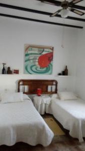 two beds in a room with a painting on the wall at El Cercón de Candelo in Magacela