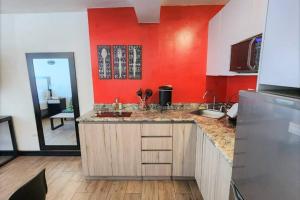 a kitchen with a sink and a red wall at DSt4 Well stocked studio in zone 15 in Guatemala