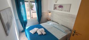 a bedroom with a blue bed with towels on it at MAREE SOL RESIDENCE Camere e Appartamenti in Torre San Giovanni Ugento