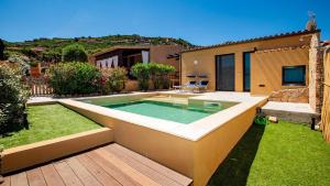a swimming pool in a garden with a house at Villa Vincent in Costa Paradiso