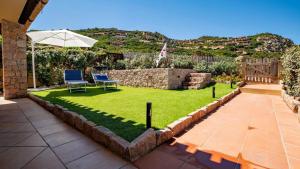 a garden with two chairs and an umbrella at Villa Vincent in Costa Paradiso +22 photos