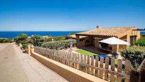 a house with a fence next to the ocean at Villa Vincent in Costa Paradiso