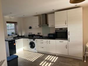 a kitchen with white cabinets and a washing machine at Great Ambience 3-Bedroom for Groups & Contractors in Rubery