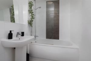 a white bathroom with a sink and a bath tub at Heart of the city 1 bed flat Queenshouse in Sheffield +6 photos