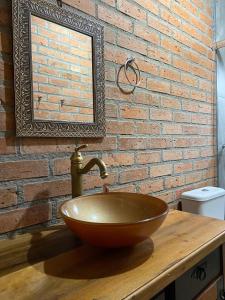 a bathroom with a bowl sink in front of a brick wall at Refúgio Rota das Nuvens in Bom Jardim da Serra