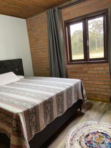 a bedroom with a bed and a window at Refúgio Rota das Nuvens in Bom Jardim da Serra