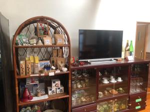 a entertainment center with a television and a shelf of items at ティダ民宿結の家 in Sekirubu