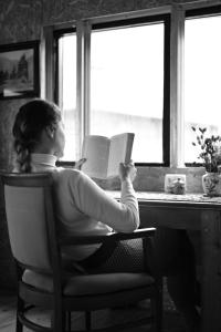 a woman sitting in a chair reading a book at Zeta Camping in Jut'a