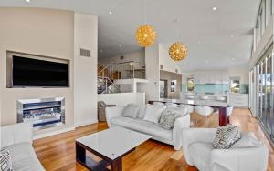 Il comprend un salon doté d'un mobilier blanc et d'une télévision à écran plat. dans l'établissement Waikiki 1 Waikiki Way Middleton - Linen Included, à Middleton