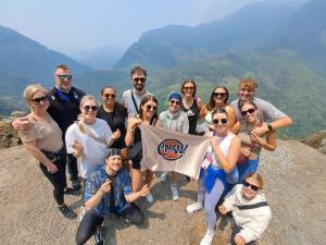 a group of people standing on a mountain holding a flag at Cheers Hostel Hanoi in Hanoi