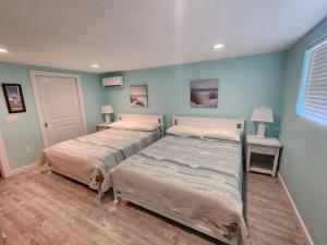 two beds in a bedroom with blue walls at Coastal Cottage Bay House in Palacios