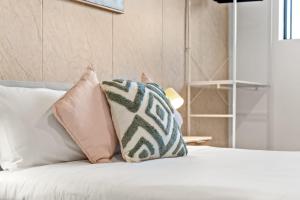 a white bed with pillows on top of it at Boutique Queen Room - Centrally Located at Glenfield - Shared Bathroom in Glenfield
