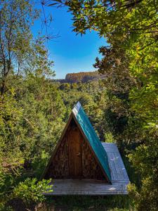 a small cabin with a blue roof in the woods at Parque Repuleufu Chiloé in Ancud