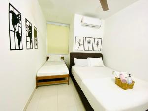 deux lits dans une chambre aux murs blancs dans l'établissement Alyn Home Kluang V Netflix, à Keluang