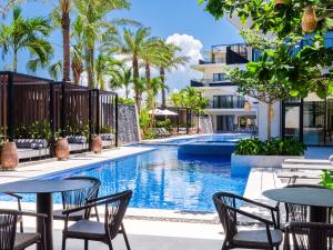 石垣島にあるseven x seven 石垣のテーブルと椅子、ヤシの木のある屋外プール