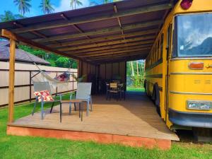 a yellow bus parked under awning with a table and chairs at Moe Bus House in Moorea +6 photos