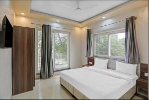 a bedroom with a large white bed and windows at Expo View INN in Greater Noida +11 photos