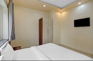 a bedroom with a white bed and a television at Expo View INN in Greater Noida