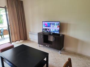 a living room with a table and a flat screen tv at Panorama Stoykite Belvedere in Stoykite