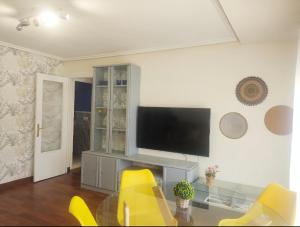a living room with a television and yellow chairs at Apartamento céntrico con Wifi Avilés in Avilés