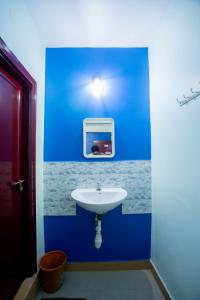 a bathroom with a blue wall with a sink at Sree Theja Residency in Anantapur