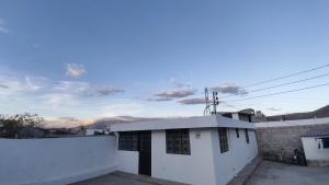 a white house with a white wall and a sky at Acogedora Casa Completa con jacuzzi privado in Quito
