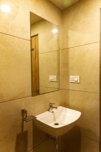 un baño con lavabo y espejo en Adarsh Palace Hotel, en Bhopal